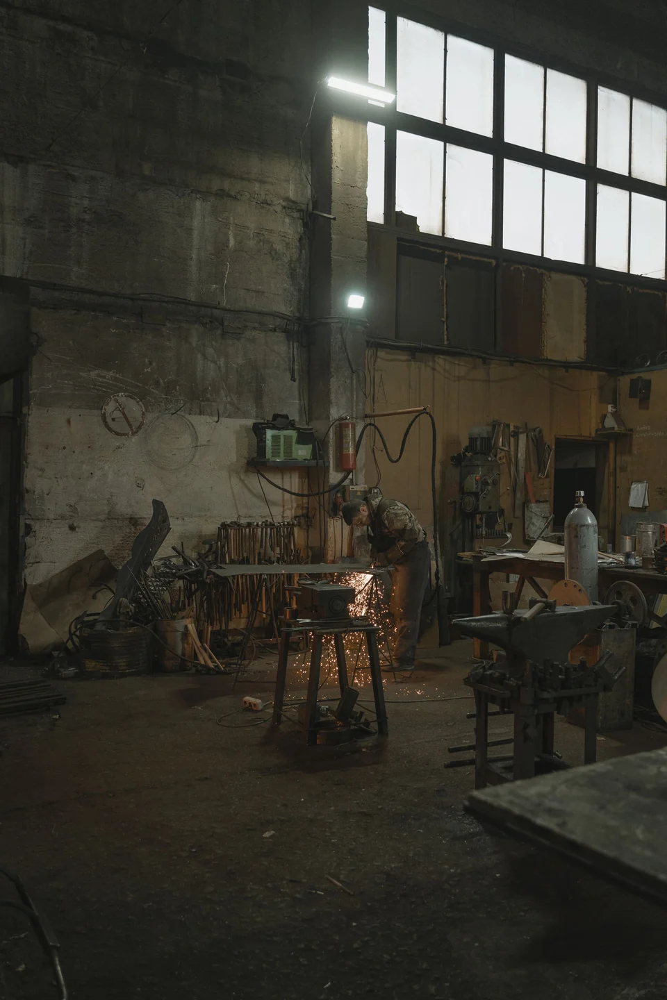 Osoba obrabiająca metal przy stole w warsztacie — fotografia referencyjna
